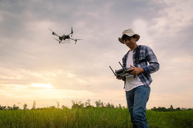 Especialista agrícola controla drones agrícolas con control remoto para rociar fertilizantes y pesticidas en campos de arroz Agricultura 5g Agricultura inteligente Concepto de tecnología inteligente