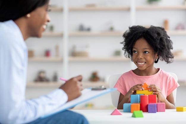 Especialista en desarrollo infantil teniendo sesión con una niña alegre