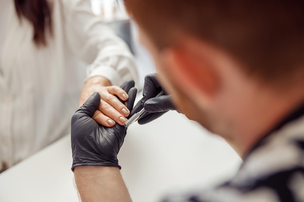 Especialista em manicure fazendo cuidados com as unhas para cliente no estúdio de beleza