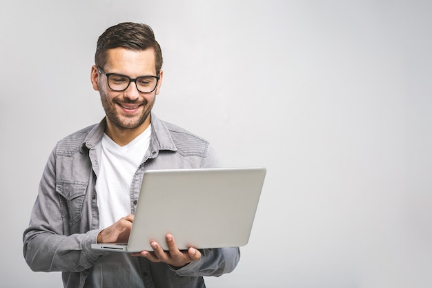 Foto especialista em negócios confiante. confiante jovem bonito na camisa, segurando o laptop e sorrindo em pé contra um fundo branco