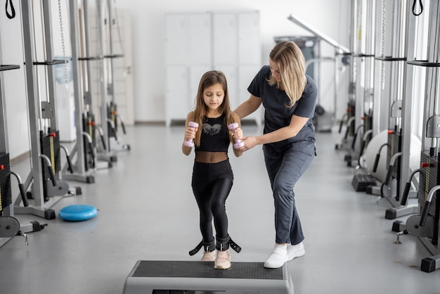 Especialista em reabilitação, ajudando a menina a fazer exercícios na academia