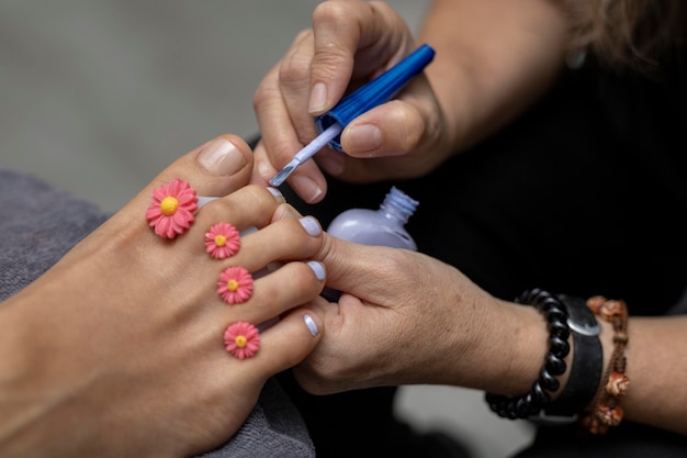 Especialista em um salão de beleza dando pedicure pintando as unhas dos pés com tinta brilhante