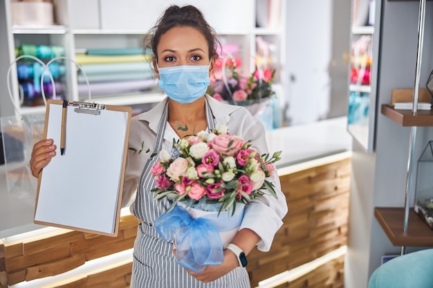 Especialista experto en flores sosteniendo un ramo y un portapapeles