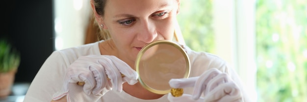 Especialista feminina verifica moeda de ouro com lupa estimando o valor do conceito de antiguidades