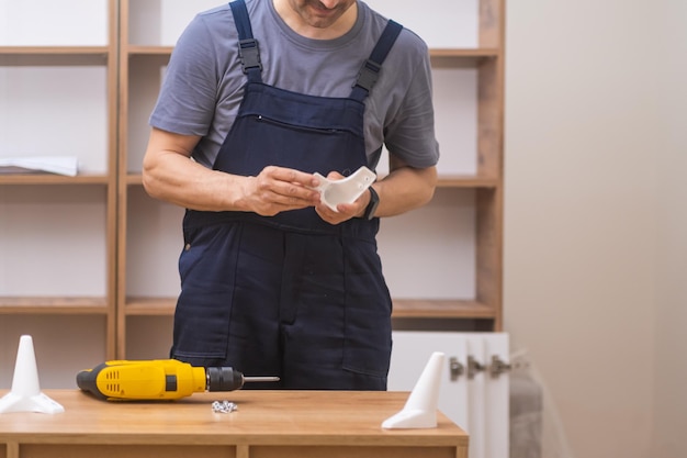 Foto especialista en instalación de muebles montando estantes de madera fijando patas con destornillador eléctrico