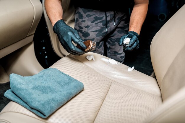 Especialista limpia el asiento del coche con una espuma especial. Tema de detalle de coche