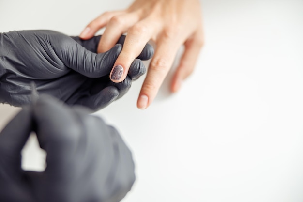 Especialista en manicura cuidando las uñas del cliente en el estudio