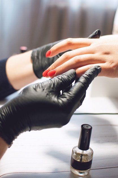 Especialista en manicura en guantes negros. Cuida las uñas.