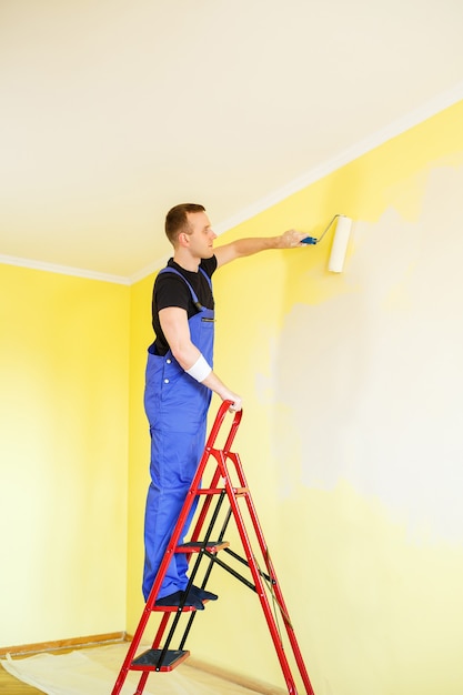 Especialista masculino pinta a parede com tinta interna, conceito de reparo