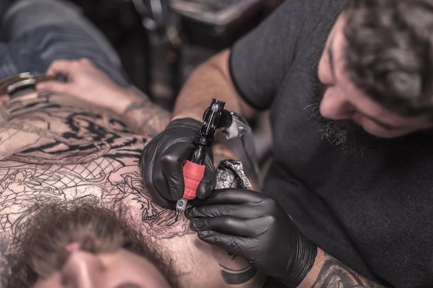 El especialista en tatuajes hace un estudio de tatuajes de arte del tatuaje.