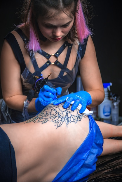 Foto especialista en tatuajes que trabaja en un dispositivo de máquina de tatuaje profesional en un taller de estudio.