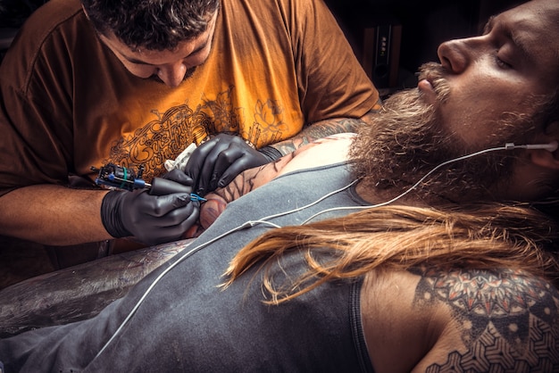 Especialista en tatuajes en el trabajo en el salón de tatuajes