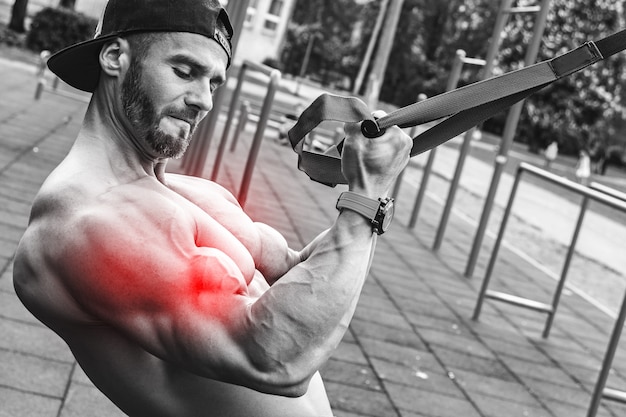 Foto especialização em bíceps. homem durante treino com alças de suspensão na rua