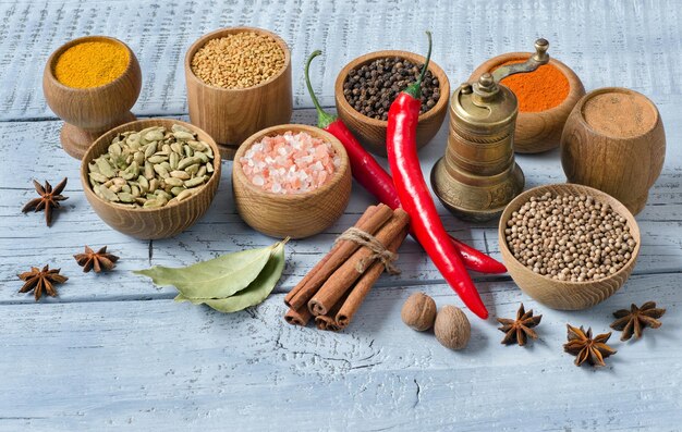 Especiarias para a culinária indiana. Sal, pimenta, gengibre, pimenta, coentro, açafrão e outros sobre fundo azul de madeira.