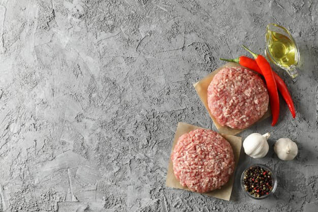 Foto especias y papel de horno con carne picada en gris, vista superior