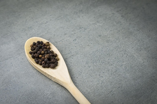 Especias de pimienta negra en cuchara de madera