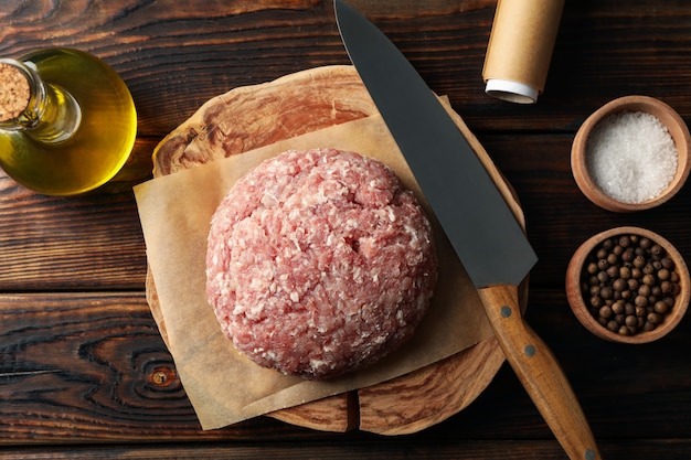 Foto especias y tabla con carne picada y cuchillo en madera, vista superior