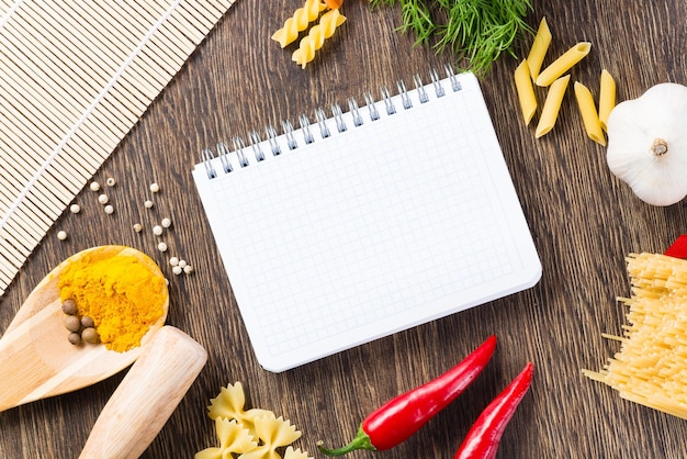 Especias y verduras alrededor del cuaderno.