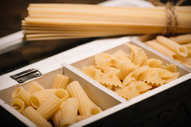 Una especie de pasta de rigatoni, penne, farfalle butterlfly, cerrar dentro de una caja de madera