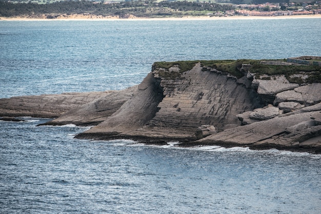 Espectacular paisaje de costa rocosa y herbosa de mar ondulante bajo el cielo gris nublado en Cabo Mayor