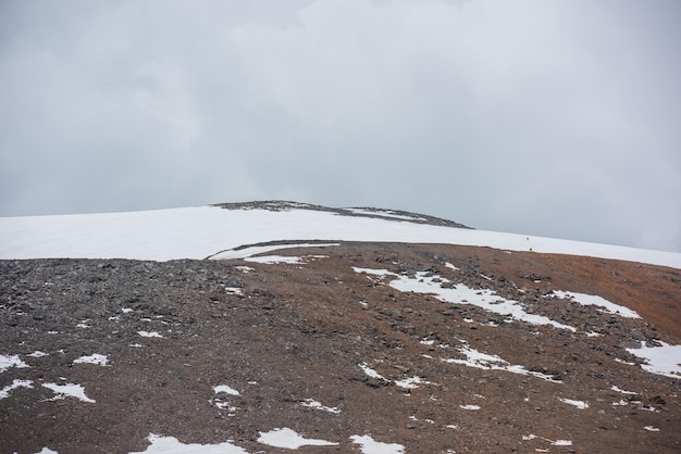 Espectacular paisaje con una enorme montaña rocosa con una cúpula de montaña nevada bajo un cielo nublado gris Impresionante paisaje con una alta montaña nevada en forma de cúpula en el centro en un clima nublado Cima de la montaña en forma de cúpula