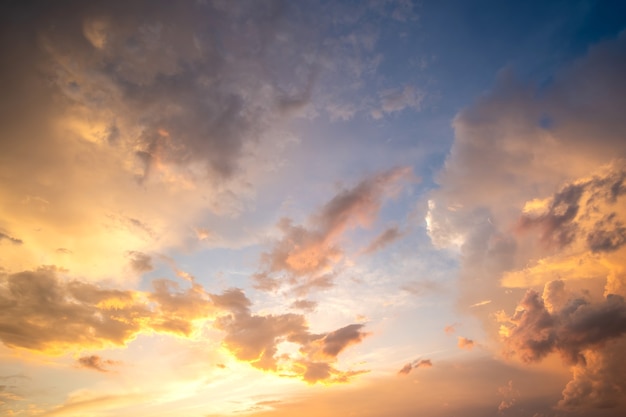 Espectacular paisaje nublado al atardecer con nubes hinchadas iluminadas por el sol poniente naranja y el cielo azul