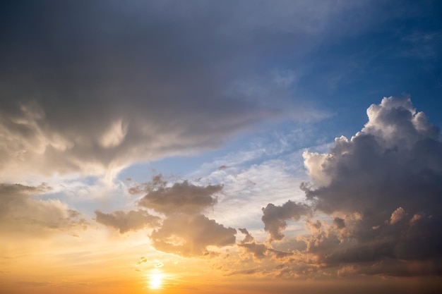 Espectacular paisaje de puesta de sol amarillo con nubes hinchadas iluminadas por el sol poniente de color naranja y el cielo azul.