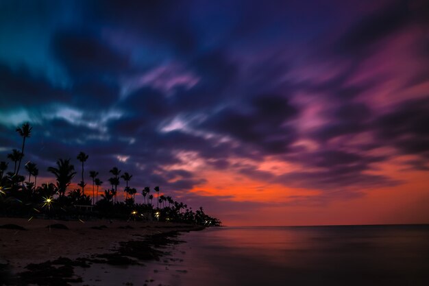 Espectacular puesta de sol sobre la exótica playa, con palmeras.