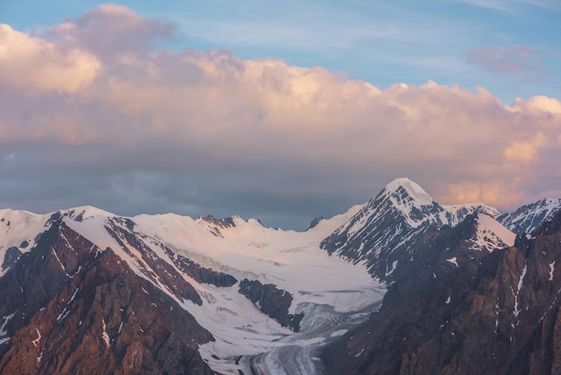 Espectacular vista aérea al pico de la alta montaña nevada temprano en la mañana al amanecer Impresionante paisaje con montañas nevadas iluminadas por el sol en el cielo nublado al amanecer Paisaje escénico con un gran glaciar en los colores del amanecer