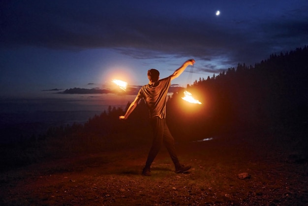 Espectáculo de fuego por el hombre en las montañas de los Cárpatos de noche Hermoso paisaje