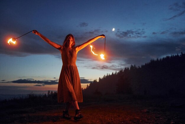 Espectáculo de fuego de una mujer vestida en la noche Montañas de los Cárpatos Hermoso paisaje