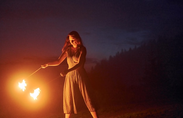 Espectáculo de fuego de una mujer vestida en la noche Montañas de los Cárpatos Hermoso paisaje