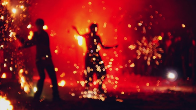 Foto espectáculo de fuego nocturno baila con destellos en la playa.