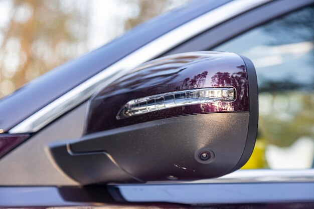 Espejo lateral de la vista trasera de un automóvil moderno con una cámara de vista del terreno, asistente de estacionamiento y automóvil