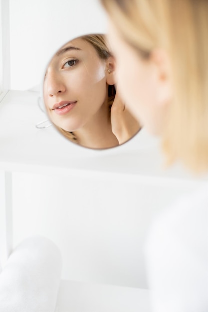 Espejo de mujer para el cuidado de la piel facial cosmetología matutina