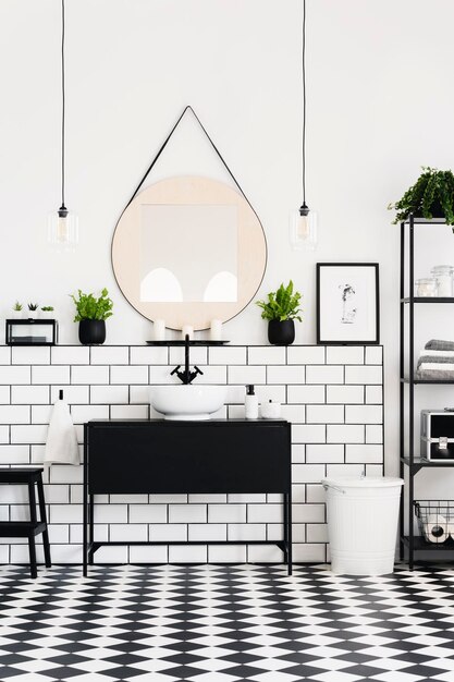 Espejo entre plantas sobre lavabo negro en interior de baño de contraste con póster Foto real