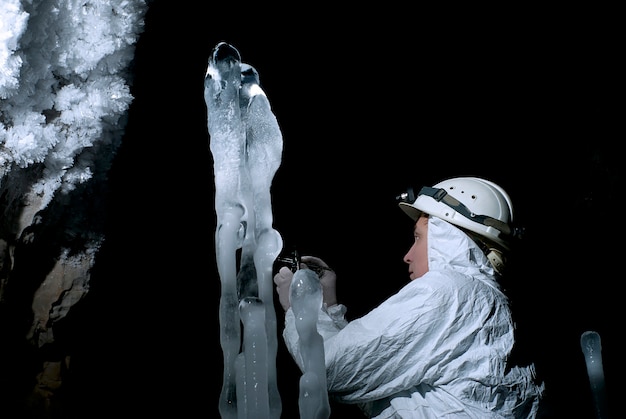 El espeleólogo toma una muestra de la estructura del hielo en el fondo de una oscuridad