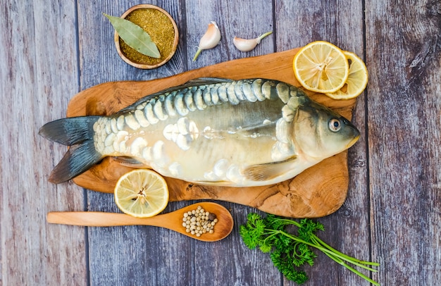 Espelhe a carpa em uma placa de corte cercada por vegetais. peixe fresco antes de cozinhar. peixe e legumes.