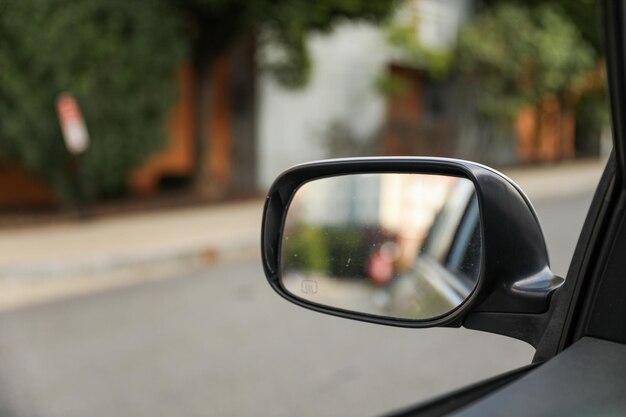 espelho lateral do carro refletindo a paisagem urbana ao pôr do sol, destacando viagens, vida urbana e autorreflexão