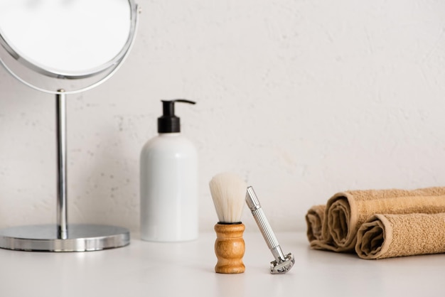 Foto espelho redondo dispensador de creme para o corpo escova de barbear navalha e toalhas em fundo branco desperdício zero