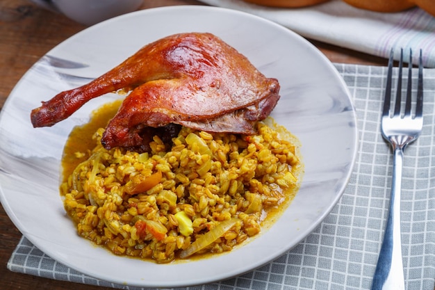 Foto espelta com legumes e uma perna de pato em um prato leve ao lado em um guardanapo sobre a mesa