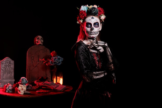 Espeluznante dama de muertos con maquillaje de calavera y colorida corona de flores, actuando como santa muerte en la celebración del día de los muertos. Hermosa diosa con traje de tradición festiva.