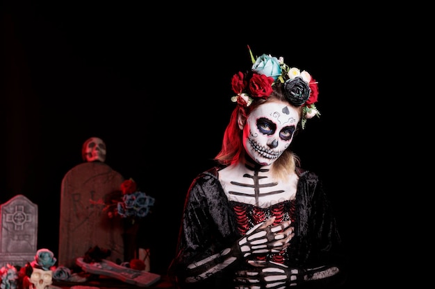 Espeluznante diosa de la muerte con maquillaje festivo y disfraz de halloween para celebrar la fiesta mexicana dios de los muertos. Mujer espeluznante como santa muerte con corona de flores, día de muertos.