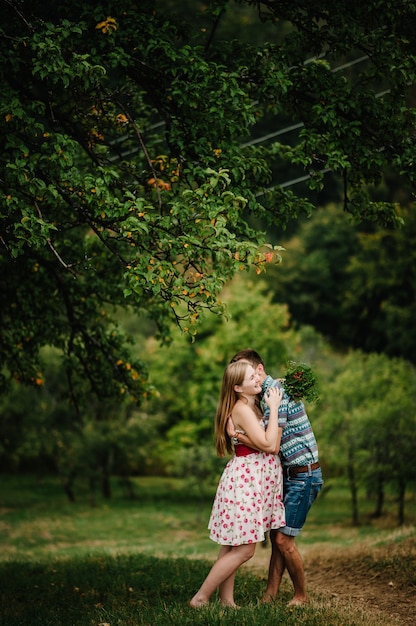 En espera bebé. familia feliz. mujer embarazada con abrazo amado esposo, descalzo sobre la hierba. vientre redondo. El sincero y tierno momento. fondo, naturaleza, parque, arbol, bosque, nueve meses. felicidad