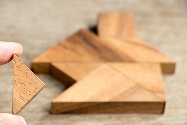 Foto espera de quebra-cabeça de madeira tangram para cumprir em forma de casa para construir o investimento de propriedade de casa de sonho