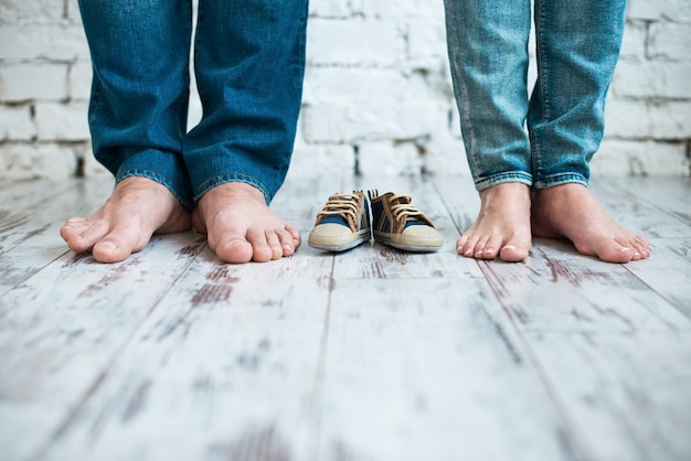 Foto esperando al bebé zapatos para niños con los pies de los padres