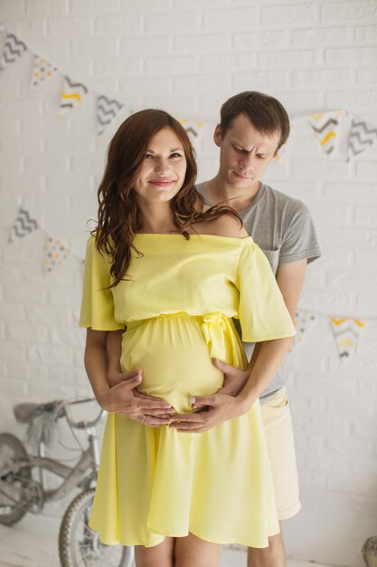 Esperando bebé. Hombre feliz abrazando a su mujer embarazada