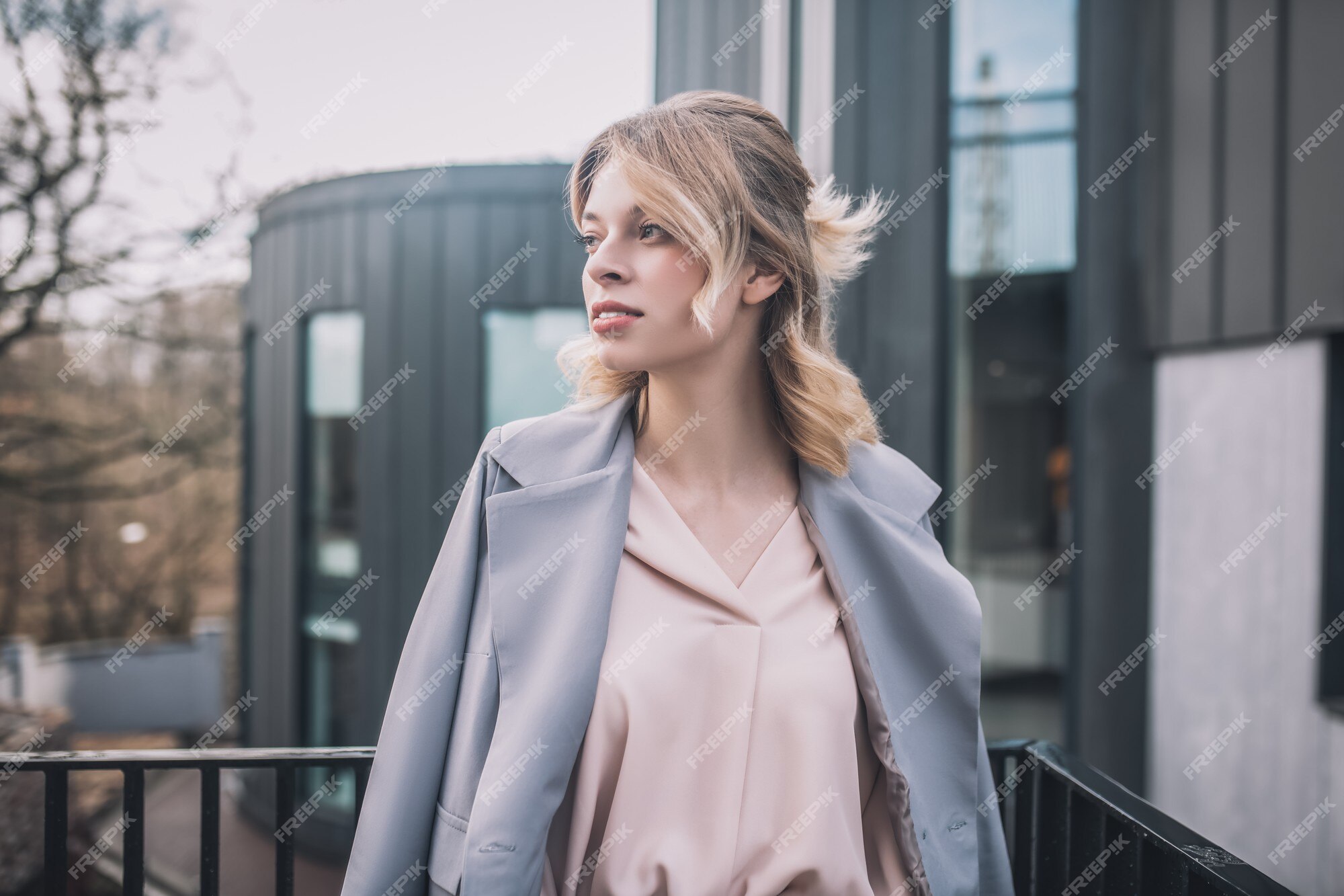 Esperando, encuentro. joven bonita rubia una chaqueta gris de negocios de pie en la mirando lado | Foto Premium