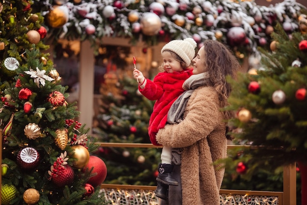 esperando o feriado de ano novo. feliz alegre mãe com filhos em uma caminhada no inverno em uma rua decorada de Natal.