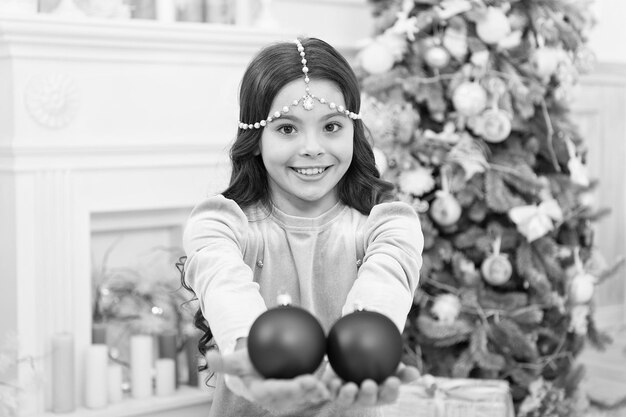 Esperando a Papá Noel Adorable niña alegre pidiendo deseo cerca de un árbol de Navidad decorado interior Víspera de año nuevo Los sueños se hacen realidad Ideas de decoración navideña Niño niña sostiene adornos navideños